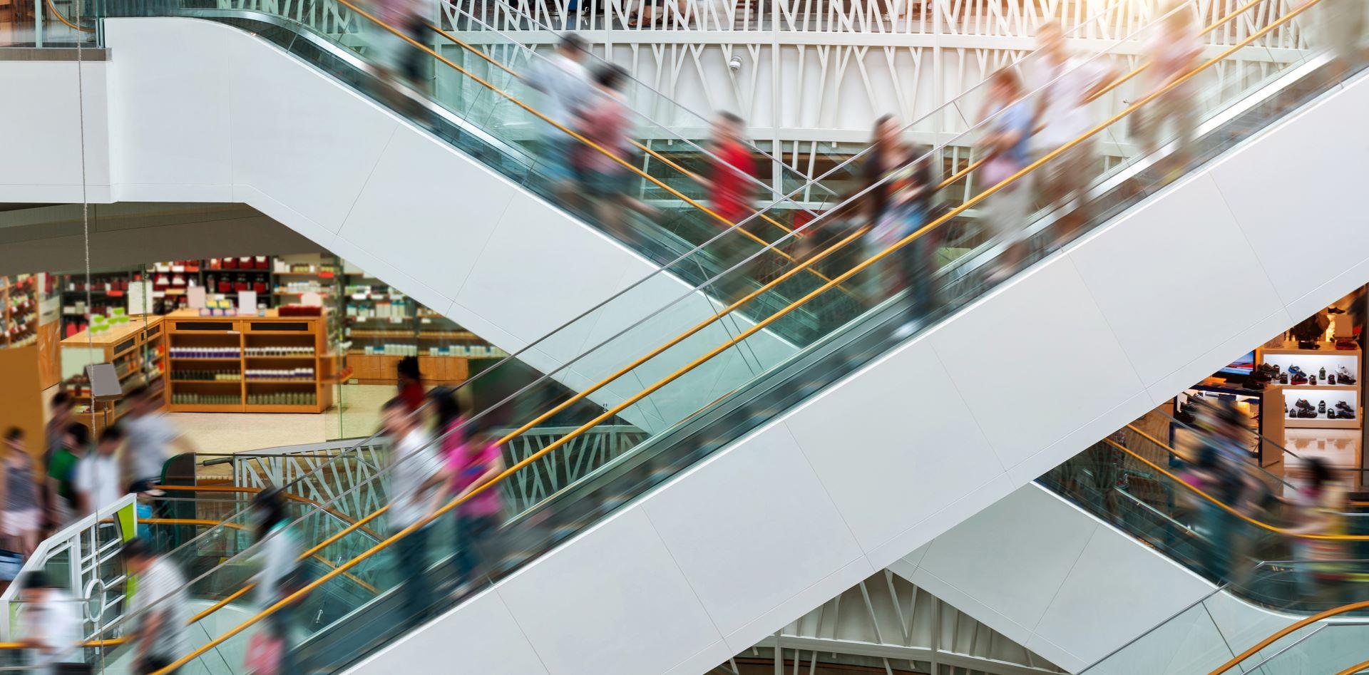 Viele Menschen auf laufenden Rolltreppen in einem modernen Einkaufszentrum, Zeitrafferaufnahme