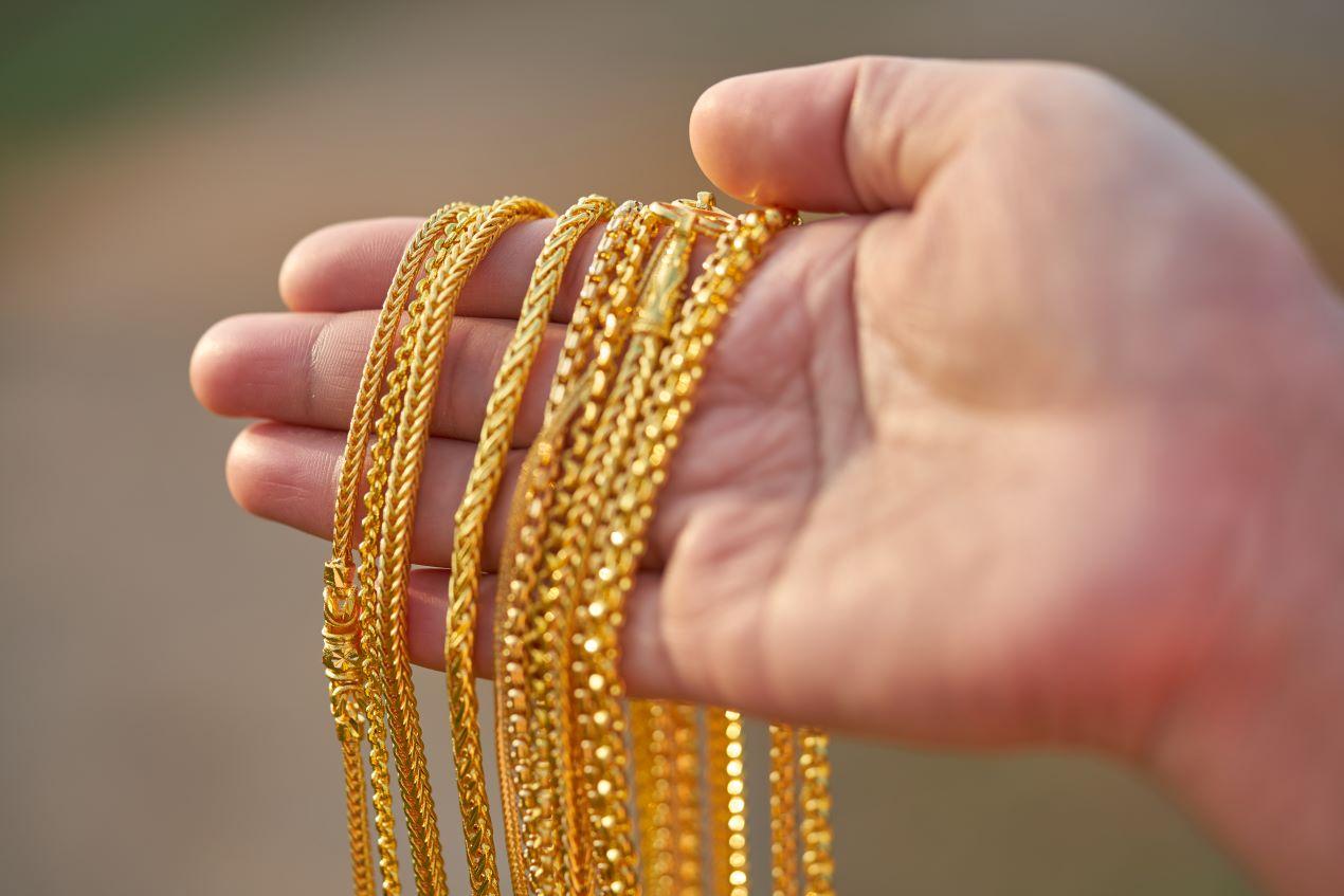 Eine Hand hält mehrere goldene Ketten mit verschiedenen Designs – Symbol für Auswahl und Eleganz bei Gold Modeschmuck.