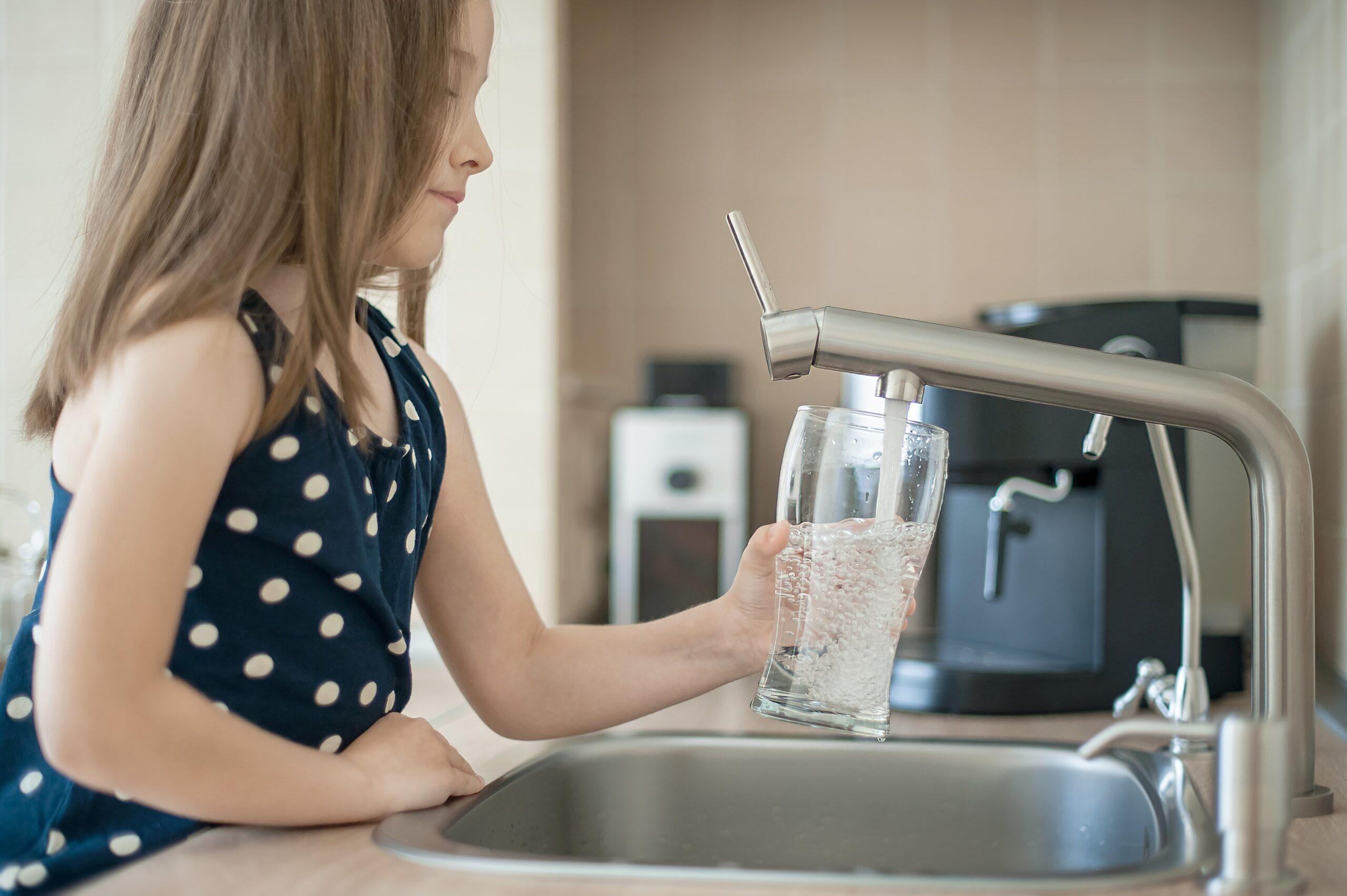 Ein Kind gießt sich Wasser ein