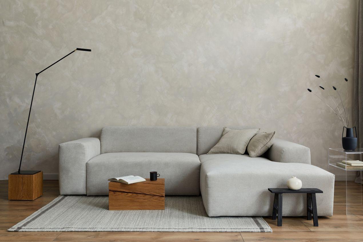 Helles Sofa Cord in modernem Wohnzimmer mit schlichter Wand, Holzdetails und eleganter Stehlampe