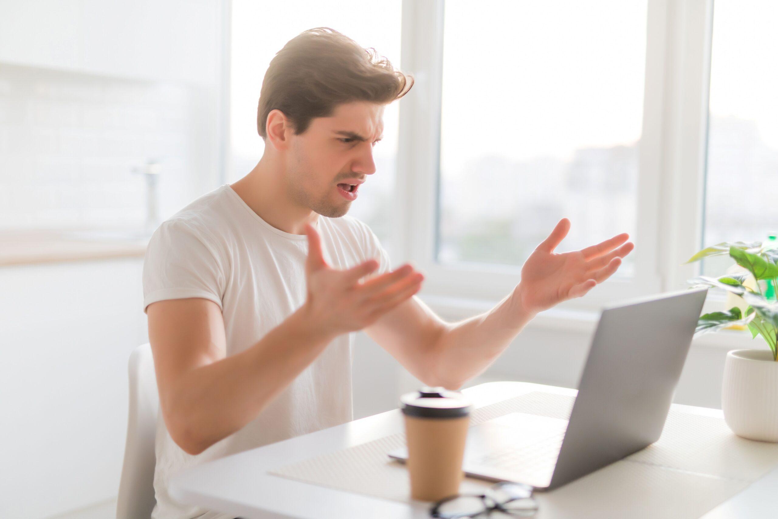 Eine Person sitzt vor einem Laptop und ärgert sich, weil etwas nicht so funktioniert wie er sich es vorstellt 
