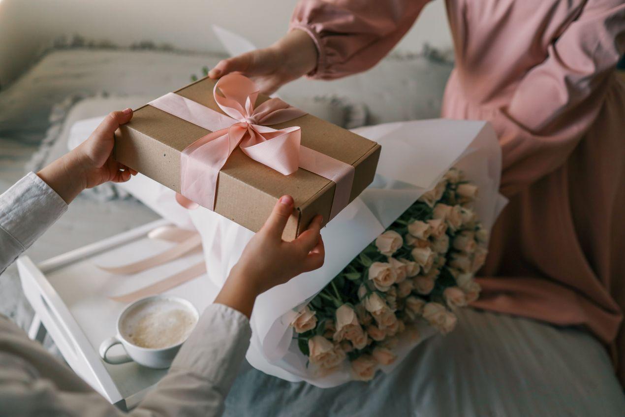 Geschenkbox mit rosa Schleife und Rosenstrauss – symbolisch für ein liebevoll verpacktes Handtuch mit Namen zum Verschenken