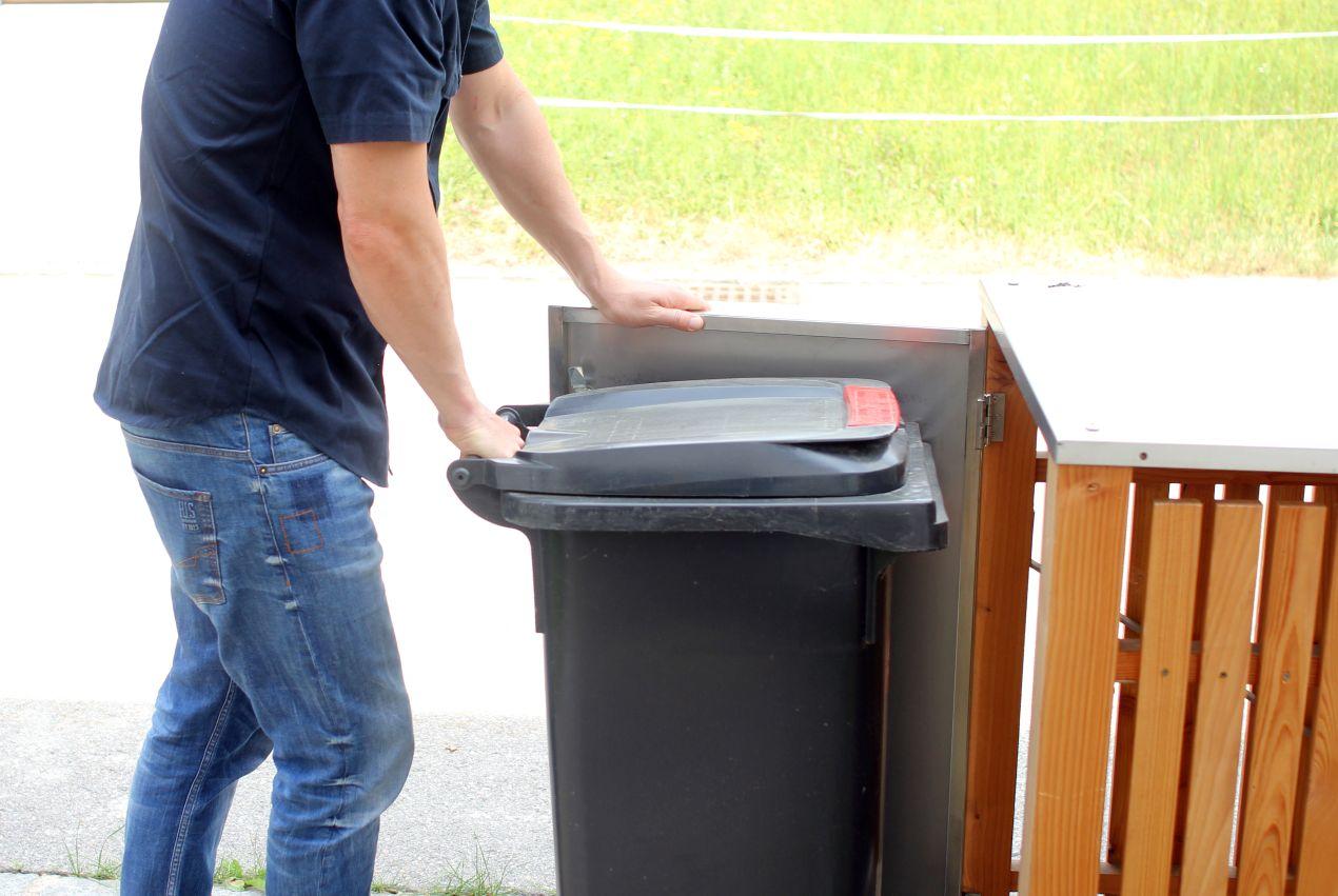 Mann öffnet eine Mülltonnenbox Metall zur Entnahme der Tonne im Alltagseinsatz